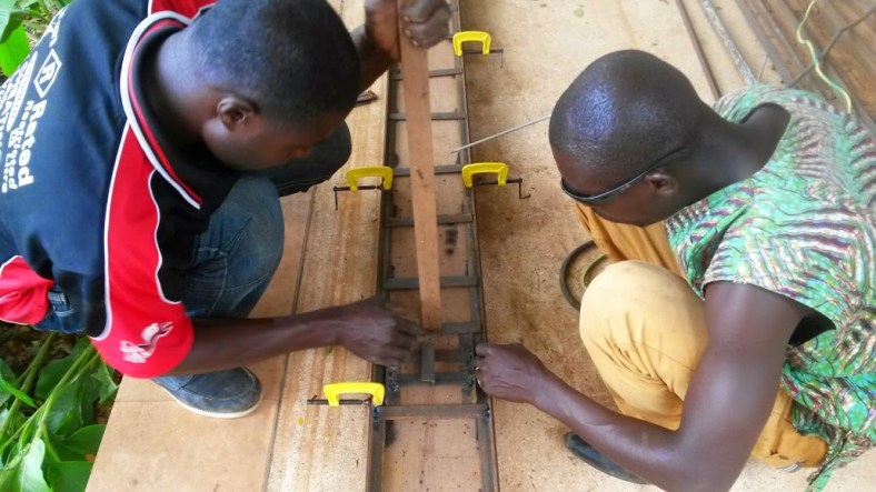 use clamps to secure 2d truss frame to jig, and a nonconductive stick (preferably wood) to push metal against wood plate of jig.
